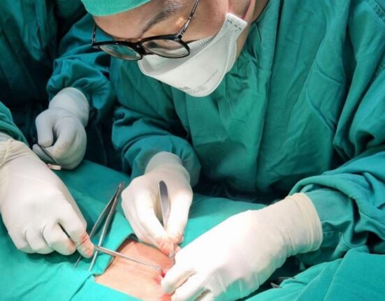 A group of medical professionals performing a surgical procedure in an operating room.