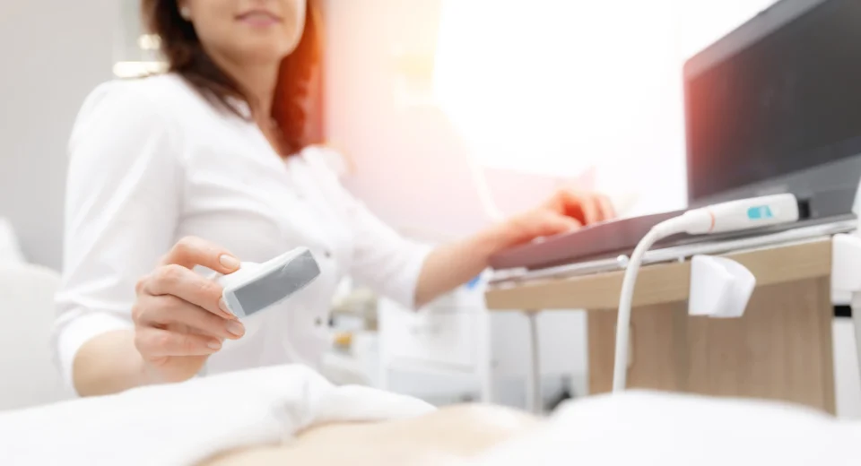 A female gynaecologist performing an ultrasound scan in a medical clinic, using advanced diagnostic imaging to assess a patient’s reproductive health.