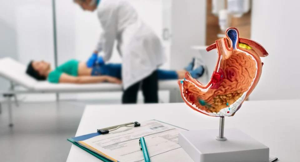 A doctor explaining stomach cancer diagnosis and treatment options to a patient in a medical consultation room.