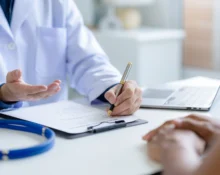 A doctor consulting a patient, taking notes on a medical document, symbolizing expert haematology consultation in Singapore and Malaysia for second opinions.