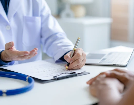A doctor consulting a patient, taking notes on a medical document, symbolizing expert haematology consultation in Singapore and Malaysia for second opinions.