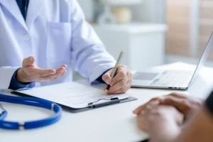 A doctor consulting a patient, taking notes on a medical document, symbolizing expert haematology consultation in Singapore and Malaysia for second opinions.